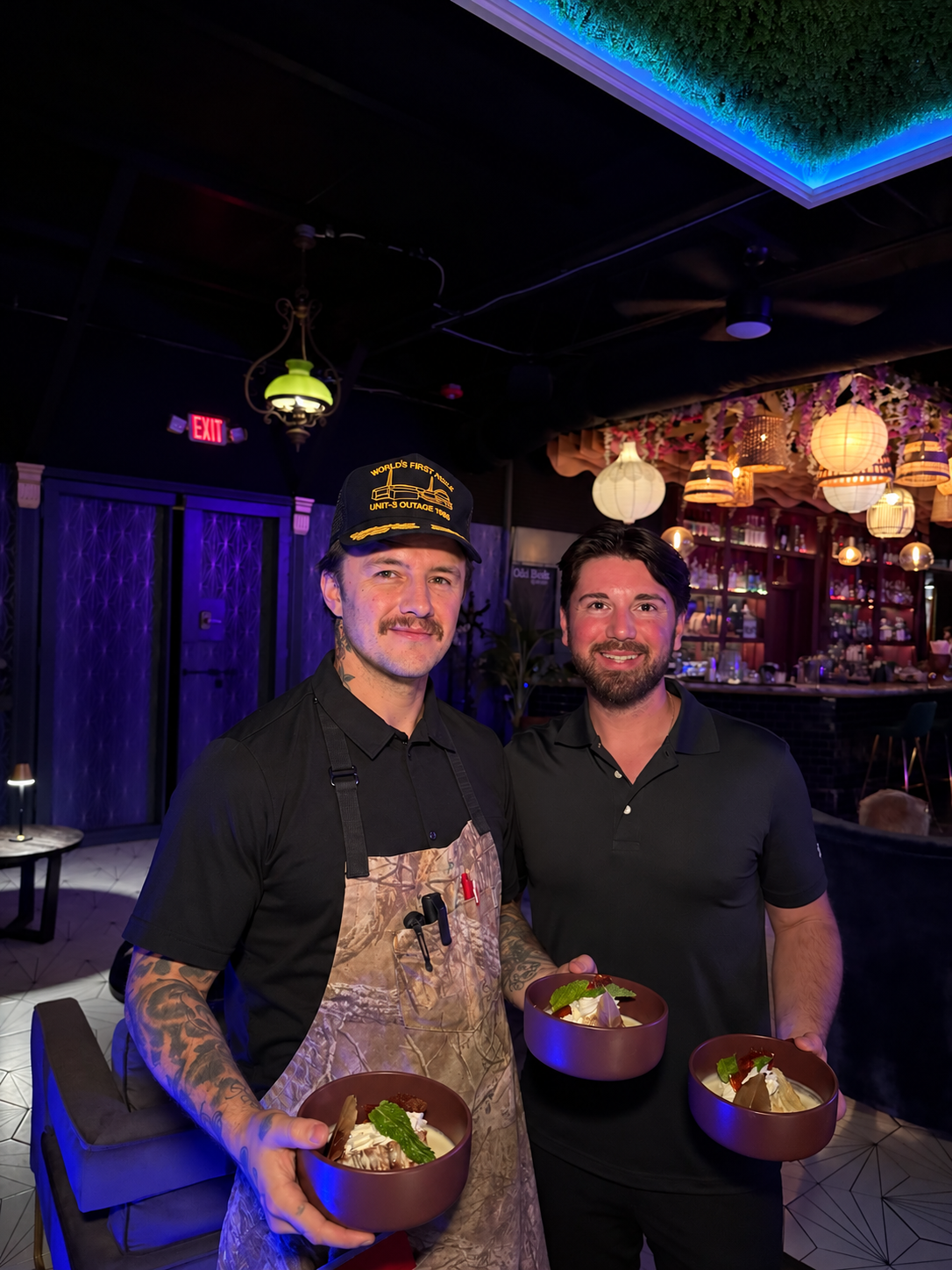 Chef Brendan and Zach holding dishes at a Supper Club gathering